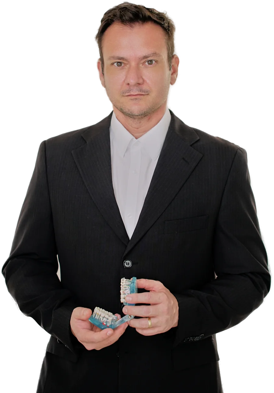 Dr. Artur Tasso Suman segurando um modelo de arcada com implantes